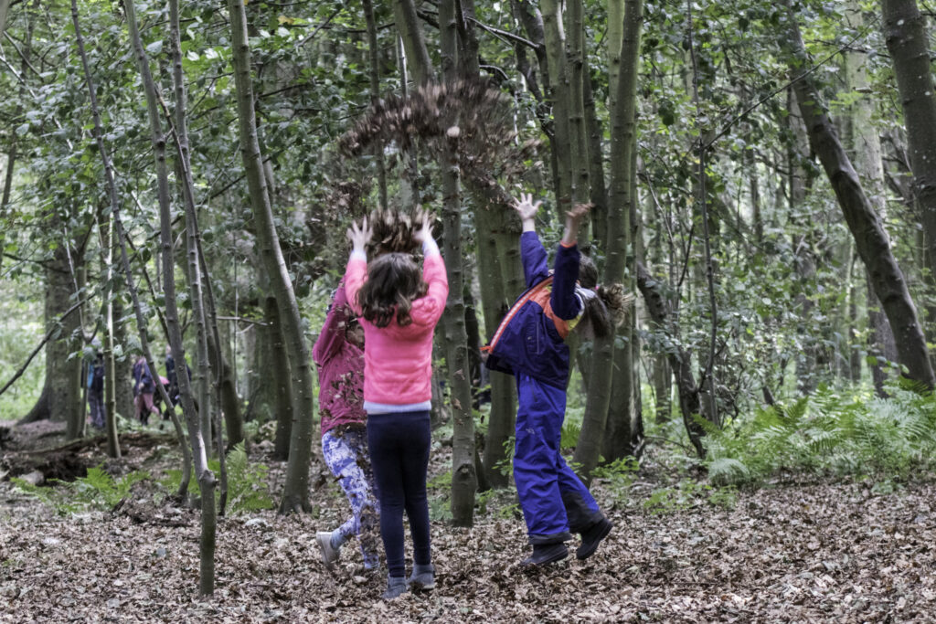 Pupils playing with leaves outside