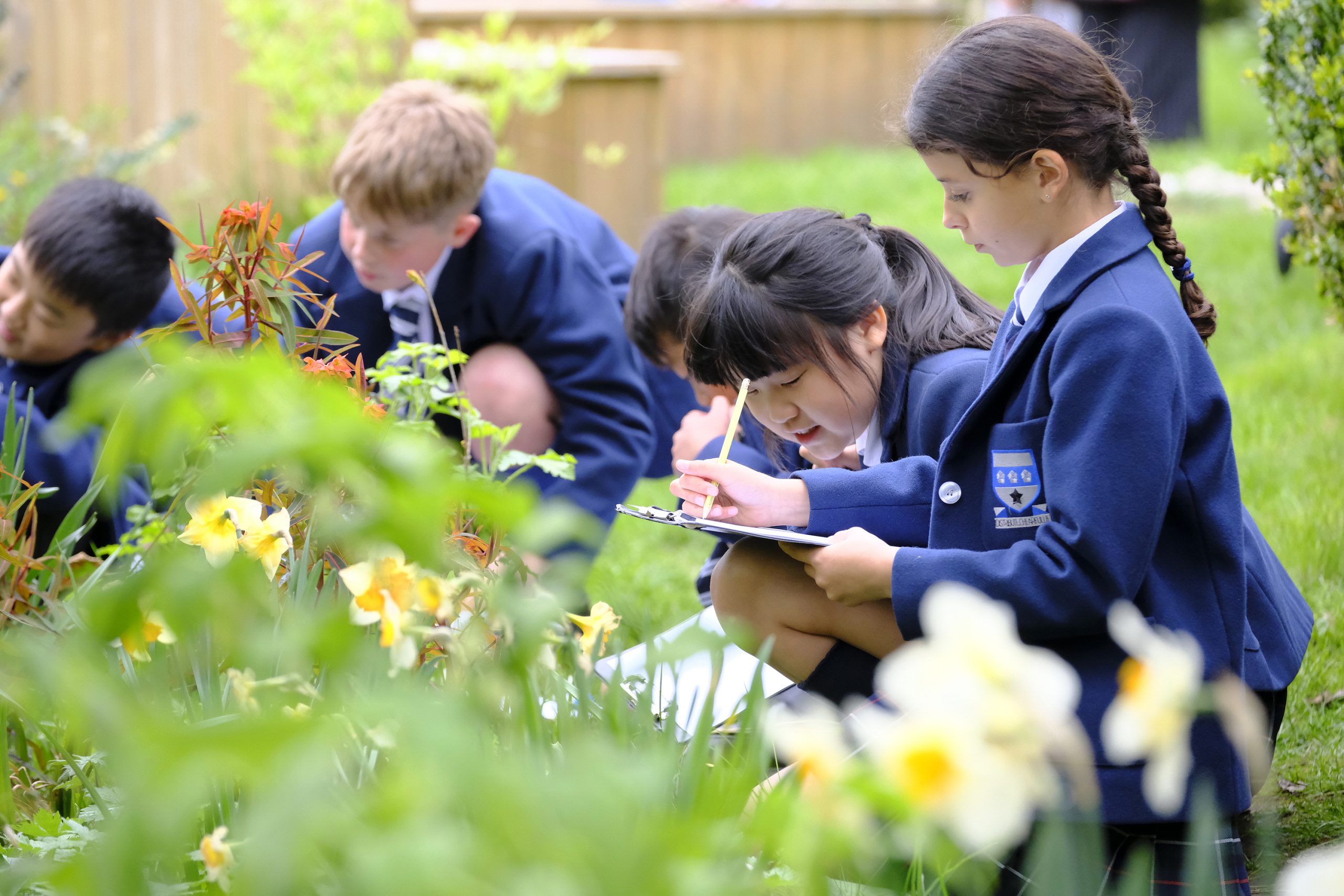 a group of children looking at plants and writing on clipboards