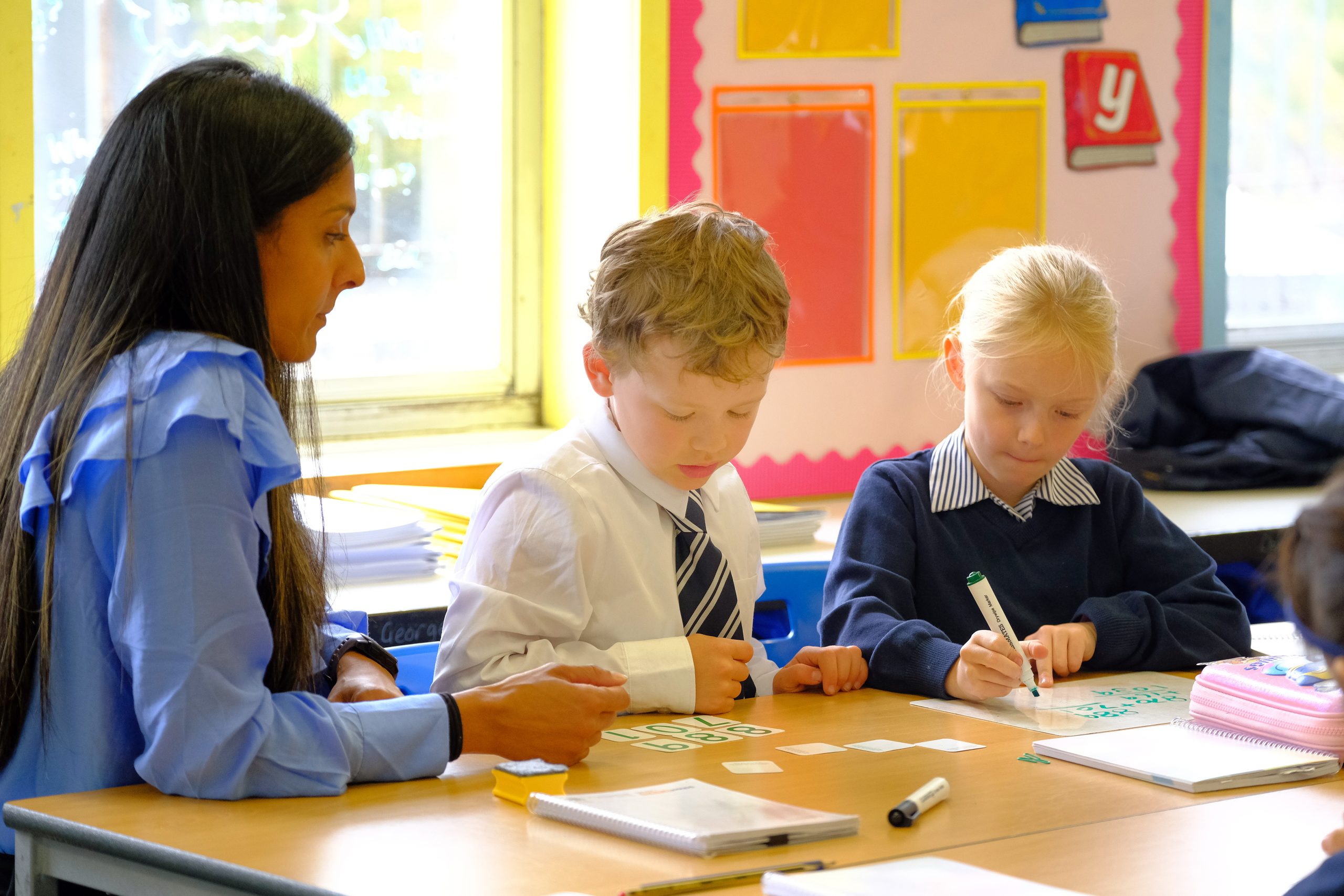 A teacher and 2 pupils writing