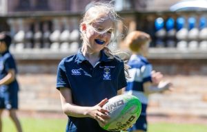 a young girl holding a rugby ball